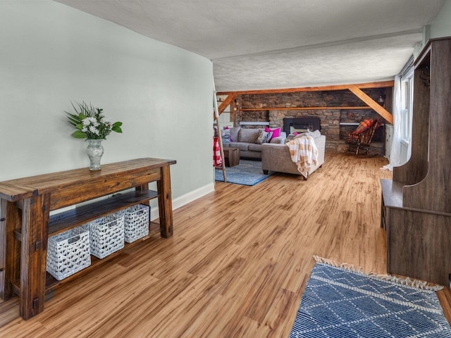 bedroom featuring a stone fireplace, hardwood / wood-style floors, and a textured ceiling