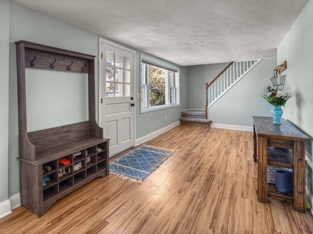 foyer entrance with a textured ceiling and light hardwood / wood-style floors