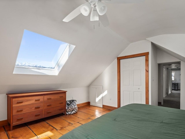 bedroom featuring ceiling fan, lofted ceiling with skylight, light hardwood / wood-style floors, and multiple windows