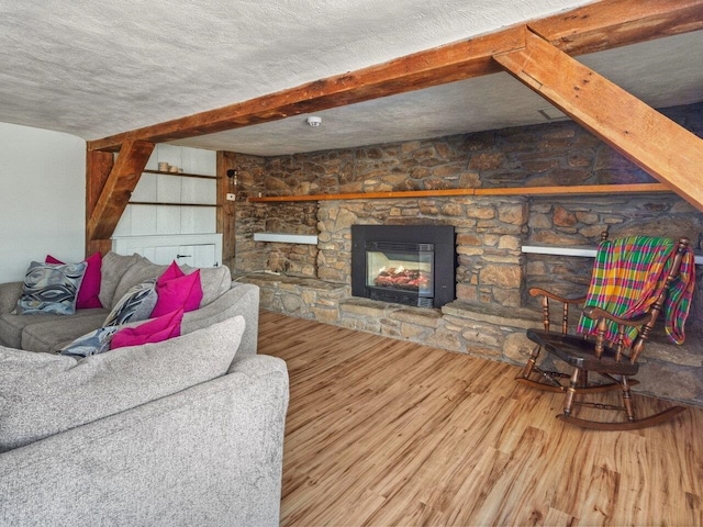 living room with hardwood / wood-style flooring, a fireplace, a textured ceiling, and beamed ceiling