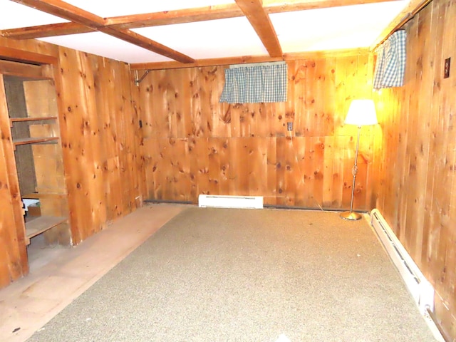 unfurnished room featuring a baseboard heating unit and wood walls