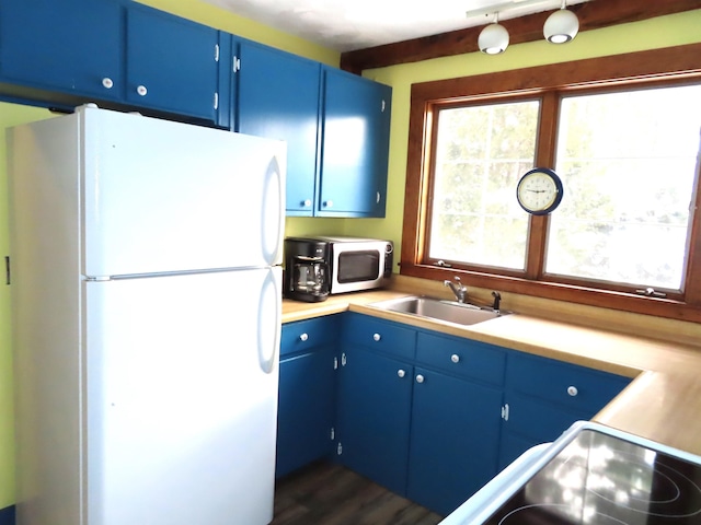 kitchen with blue cabinets, white fridge, and sink