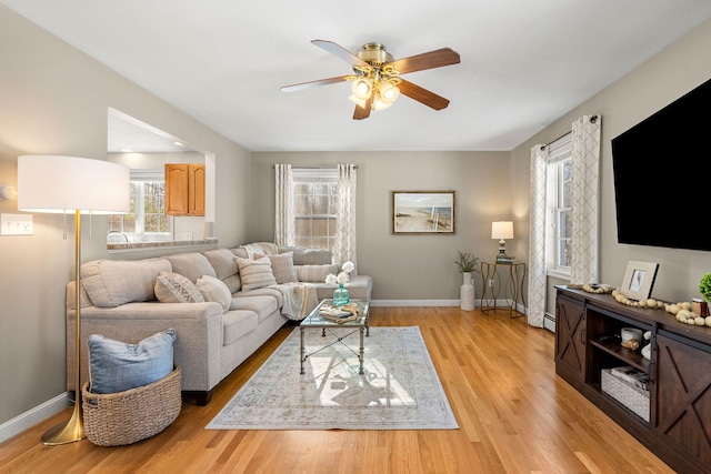 living room with ceiling fan, a baseboard heating unit, and light hardwood / wood-style floors