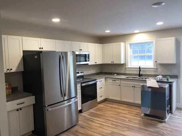 kitchen with white cabinetry, appliances with stainless steel finishes, sink, and light hardwood / wood-style floors