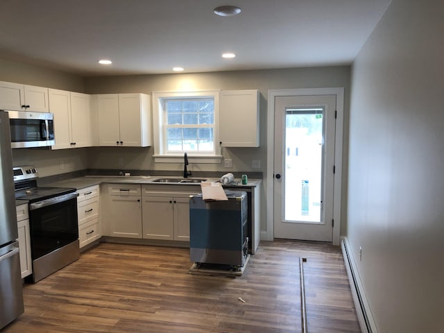 kitchen featuring white cabinetry, sink, a baseboard heating unit, and appliances with stainless steel finishes