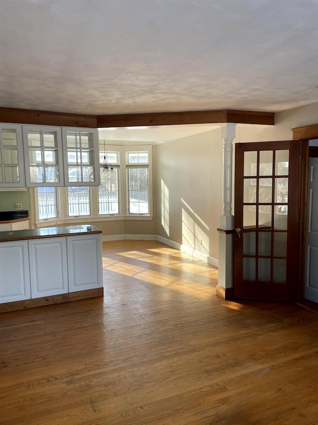 unfurnished room with beam ceiling, hardwood / wood-style flooring, and an inviting chandelier