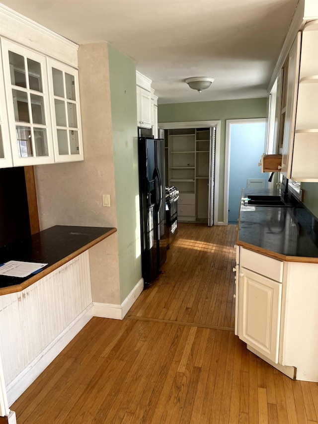 kitchen featuring white cabinetry, sink, dark hardwood / wood-style flooring, and black refrigerator with ice dispenser