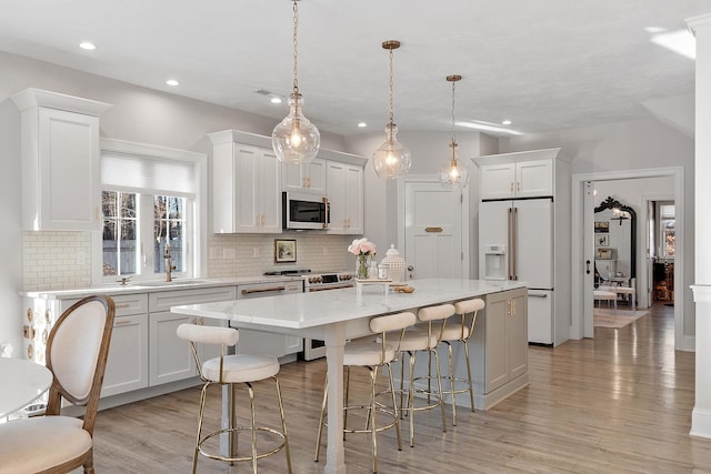 kitchen with high end appliances, white cabinetry, pendant lighting, and a kitchen island