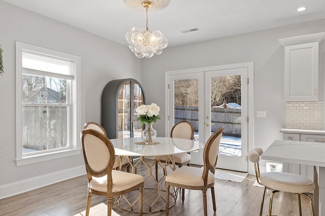 dining room with french doors, a chandelier, and light wood-type flooring