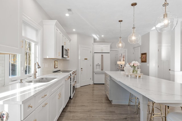 kitchen with pendant lighting, white cabinetry, sink, a center island, and white appliances