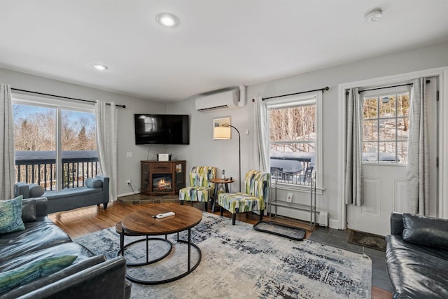 living room with wood-type flooring, plenty of natural light, a wall mounted AC, and baseboard heating