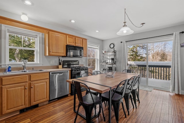 kitchen with pendant lighting, sink, light hardwood / wood-style flooring, and black appliances