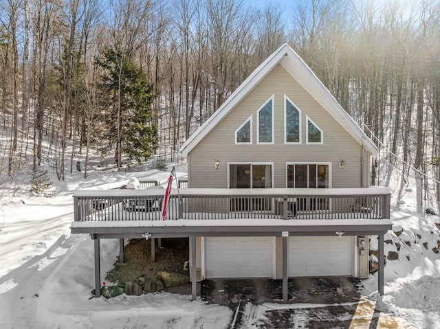 snow covered property featuring a garage and a wooden deck