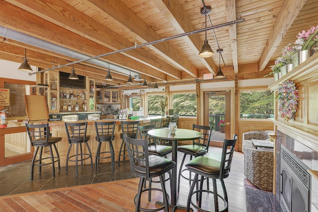 dining space featuring indoor bar, a healthy amount of sunlight, wooden ceiling, and beam ceiling