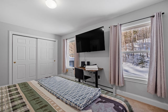 bedroom with carpet floors, baseboard heating, and a closet