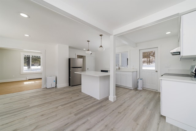 kitchen with pendant lighting, beamed ceiling, white cabinetry, stainless steel fridge, and exhaust hood