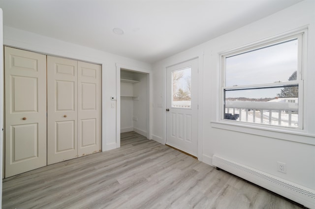 interior space with baseboard heating and light hardwood / wood-style flooring