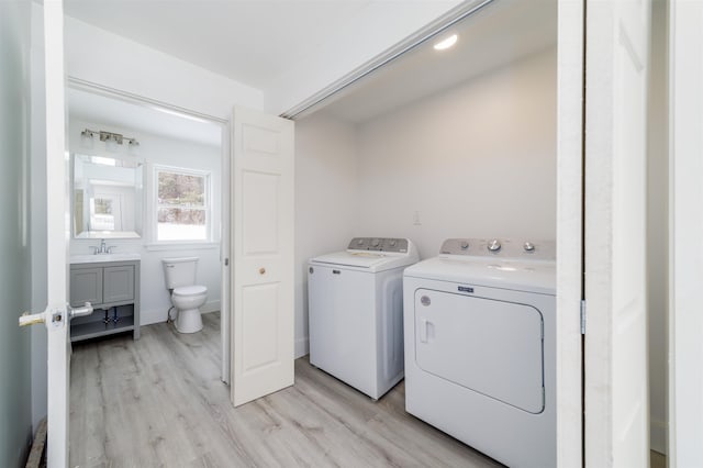 laundry room with separate washer and dryer, sink, and light hardwood / wood-style flooring