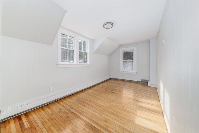 additional living space with a baseboard radiator, plenty of natural light, lofted ceiling, and light hardwood / wood-style floors