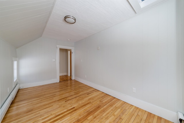 bonus room with a baseboard radiator, lofted ceiling with skylight, and hardwood / wood-style floors