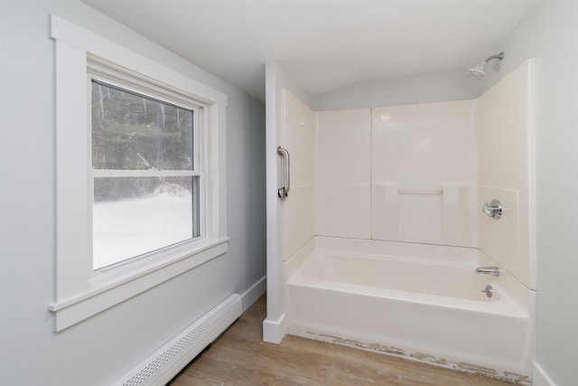 bathroom featuring a baseboard heating unit, hardwood / wood-style flooring, and bathing tub / shower combination