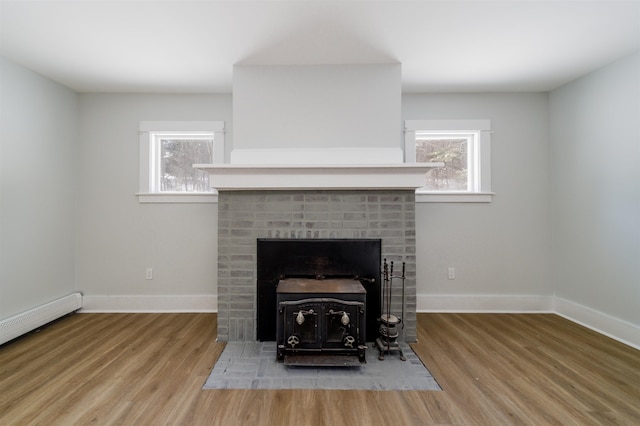 details with hardwood / wood-style flooring, a baseboard radiator, and a wood stove