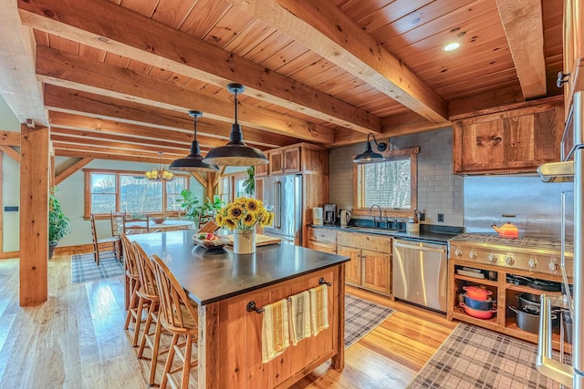 kitchen featuring pendant lighting, sink, appliances with stainless steel finishes, beamed ceiling, and light wood-type flooring