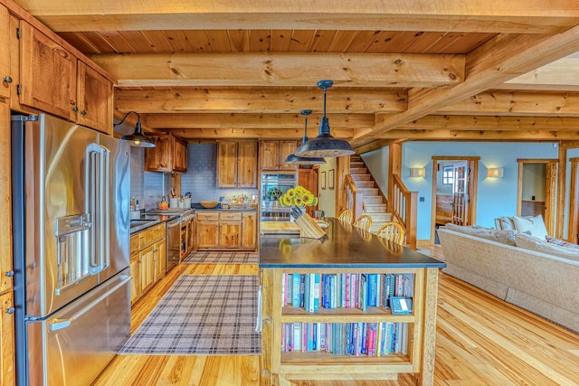 kitchen featuring beamed ceiling, stainless steel appliances, decorative light fixtures, and light hardwood / wood-style floors