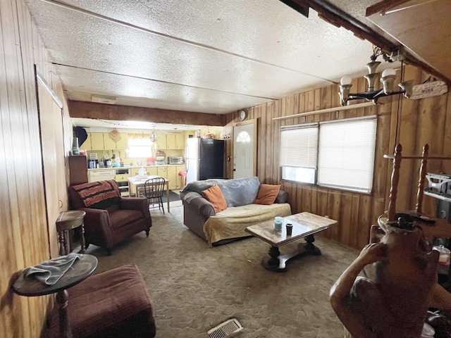 living room with carpet flooring, a textured ceiling, and wooden walls