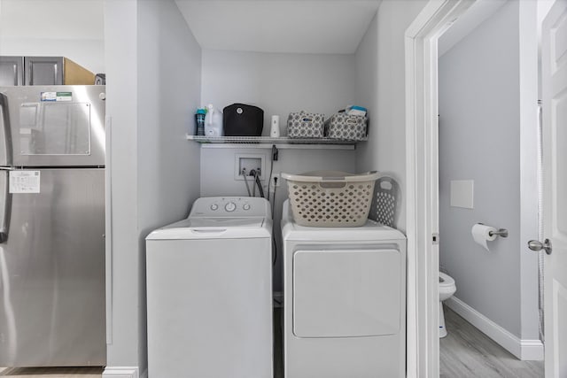 laundry area featuring independent washer and dryer and light hardwood / wood-style floors