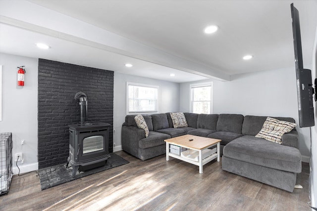 living room with beam ceiling, dark wood-type flooring, and a wood stove