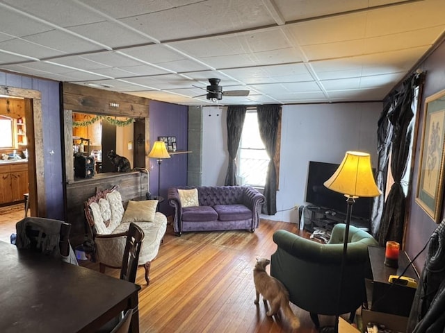 living room with ceiling fan, hardwood / wood-style floors, and wooden walls