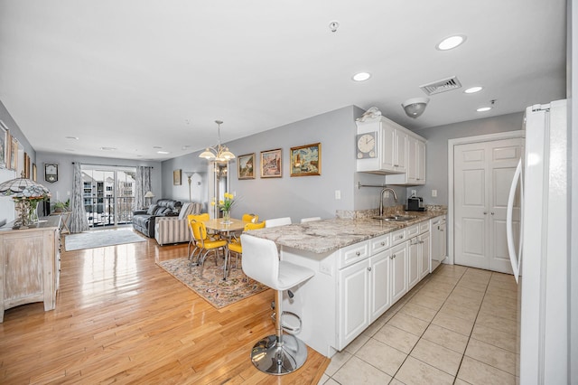 kitchen featuring sink, white cabinetry, a kitchen breakfast bar, kitchen peninsula, and white fridge