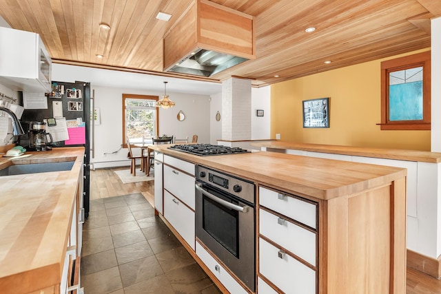 kitchen featuring stainless steel appliances, hanging light fixtures, white cabinets, and wood counters