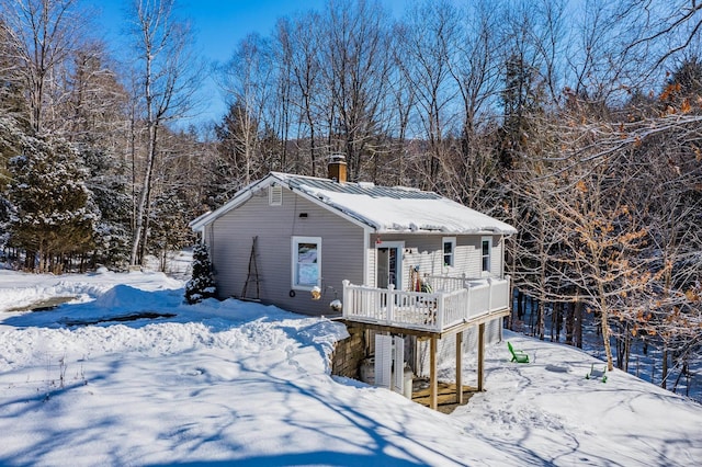 snow covered rear of property with a wooden deck