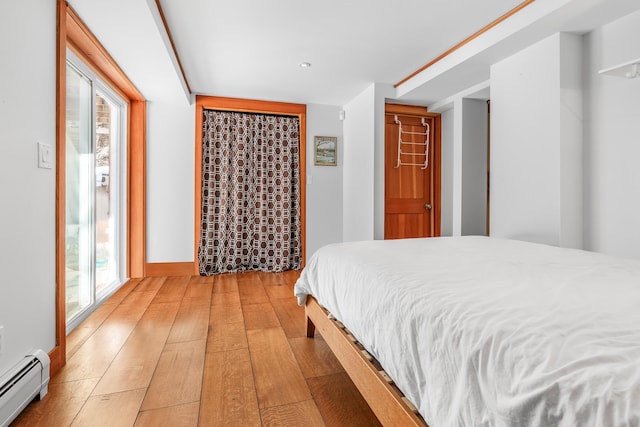 bedroom with light hardwood / wood-style floors and baseboard heating