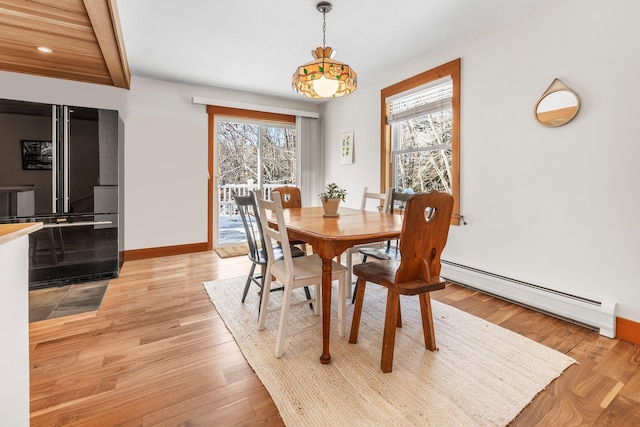 dining room with a baseboard heating unit, beamed ceiling, a healthy amount of sunlight, and light wood-type flooring