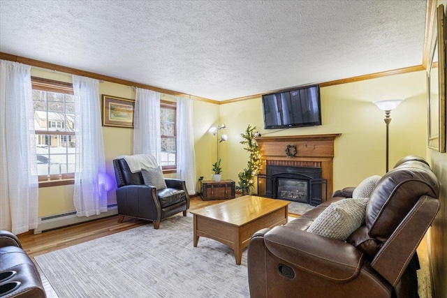 living room featuring baseboard heating, crown molding, a textured ceiling, and light wood-type flooring