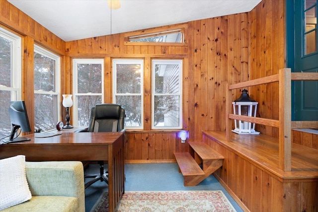 office space featuring lofted ceiling, light colored carpet, and wood walls