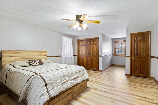 bedroom with ceiling fan, a textured ceiling, and light wood-type flooring