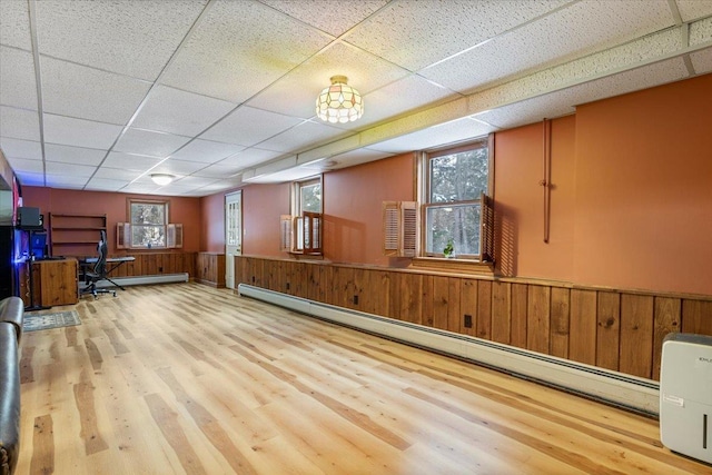 interior space with hardwood / wood-style flooring, plenty of natural light, a drop ceiling, and baseboard heating