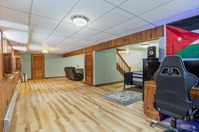 home office featuring wood walls, light hardwood / wood-style flooring, and a drop ceiling