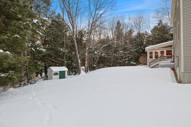 snowy yard featuring a storage unit