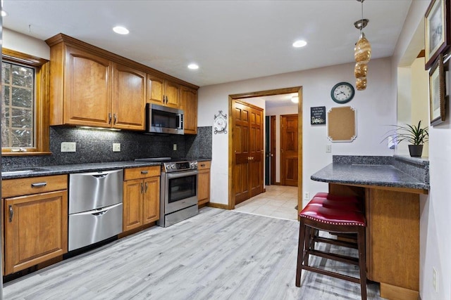 kitchen with tasteful backsplash, appliances with stainless steel finishes, a breakfast bar, and light hardwood / wood-style floors