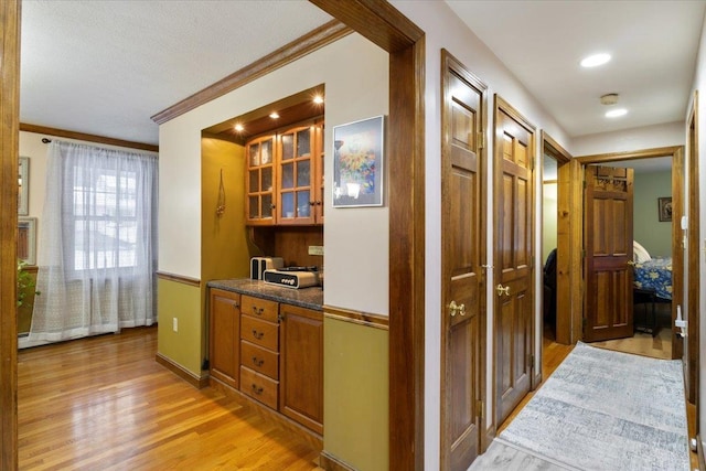 corridor with ornamental molding and light hardwood / wood-style floors