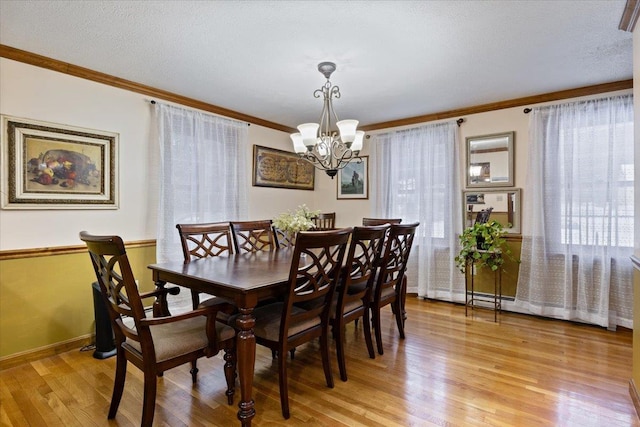 dining area featuring crown molding, a healthy amount of sunlight, an inviting chandelier, and light wood-type flooring