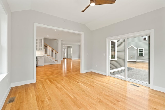 empty room with ceiling fan, lofted ceiling, and light wood-type flooring