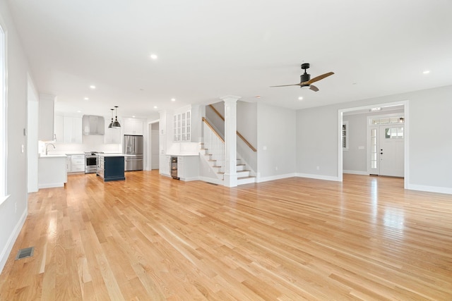 unfurnished living room with ceiling fan, light hardwood / wood-style floors, and sink