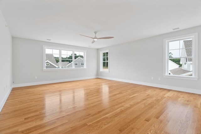 empty room featuring ceiling fan, light hardwood / wood-style floors, and a wealth of natural light