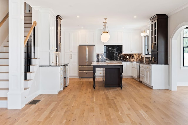 kitchen with a kitchen island, decorative light fixtures, white cabinetry, a kitchen bar, and high end fridge